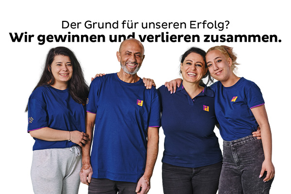 Drei Frauen und ein Mann in Blauen T-Shirts mit Piepenbrock-Logo umarmen sich und lächeln in die Kamera.